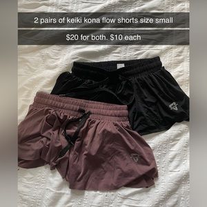 Two pairs of small Keiki Kona flow shorts. Black pair and a pinkish purple pair